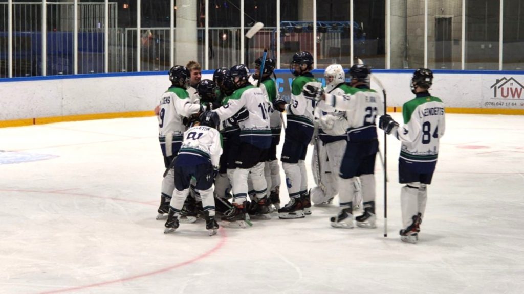Spelers van Dordrecht Lions U15 vieren samen de overwinning op Tilburg Trappers Geel met goalie Jayna Kuzee op het ijs van de Sportboulevard Dordrecht.