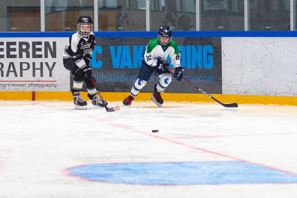 Dordrecht Lions jeugdspeler in duel om de puck langs de boarding tijdens de U9- en U11-wedstrijddag in de Sportboulevard.