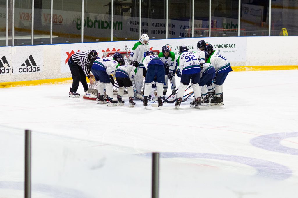 Spelers van Dordrecht Lions U15 verzamelen zich rond het doel voor de start van de wedstrijd tegen Utrecht Dragons in De Vechtsebanen.