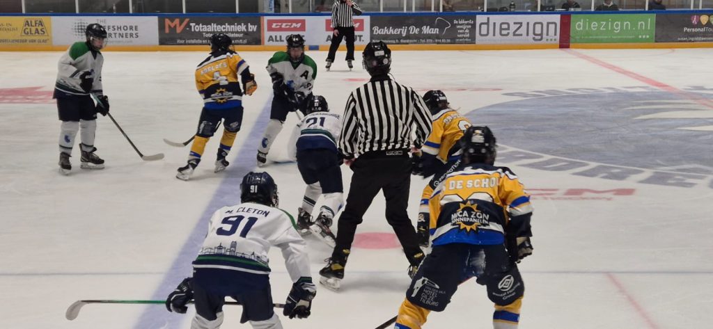 Face-off in de aanvallende zone van Dordrecht Lions U15 tegen Tilburg Trappers bij Optisport Dordrecht.