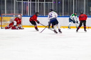 Uladzislau Chyrvony haalt uit namens Dordrecht Lions U15, terwijl de doelman van Red Eagles ’s-Hertogenbosch redding probeert te brengen. De Lions waren in de Sportboulevard Dordrecht de bovenliggende partij en wonnen het duel met 5–1.
