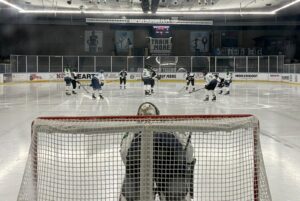 Dordrecht Lions U17 in actie tegen Amsterdam Tigers U17 in de Jaap Edenhal, gezien vanaf achter het doel tijdens een face-off.